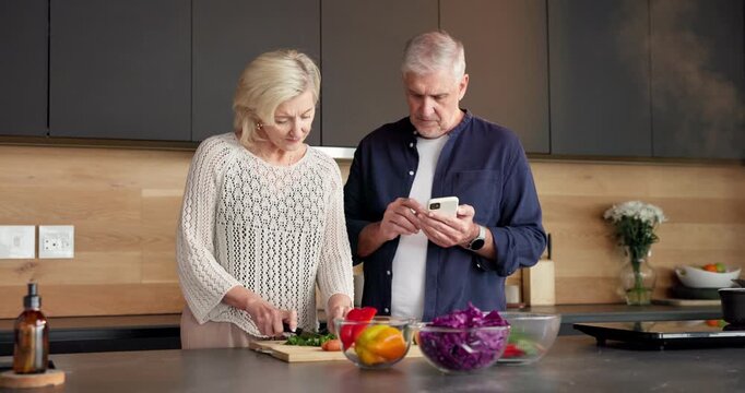 Cooking, recipe or old couple in kitchen with phone, food blog or bonding together with meal prep. Digital, help or senior people in house with tech, online tutorial or connection in culinary hobby.