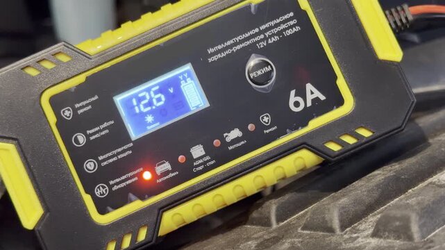 A digital battery charger displays a stable voltage level under a car hood. This reliable tool brings a reassuring feeling of safety and relief during a breakdown.