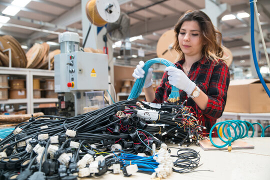 Woman assembling electrical wiring harness in industrial factory setting