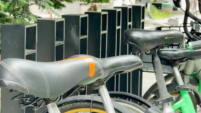 Black bicycle seats stand parked next to a modern street rack. This quiet afternoon scene brings a peaceful feeling of relaxation and readiness for a ride.