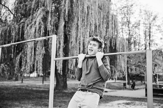 Energetic teenager enjoying workout on outdoor pull-up bar, showcasing strength and determination in natural setting.