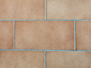 Fototapeta premium Full-frame flat lay of an architectural background featuring orange terracotta brick tiles arranged in a clean geometric running bond pattern with concrete grout lines.