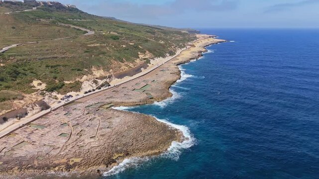 A sweeping aerial view of Xwejni reveals centuries-old salt pans etched into Gozo&rsquo;s rocky coast, where the deep blue Mediterranean meets Malta&rsquo;s timeless shoreline.