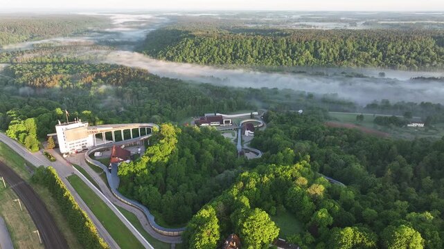 Morning Fog Drifting Through Gauja Valley Below Sigulda Bobsleigh Track. Aerial video.