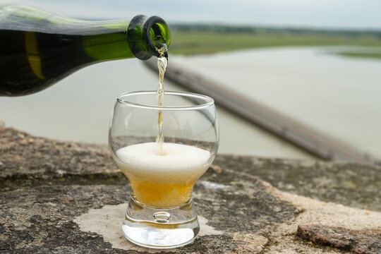 Normandy cider poured on fortress walls of Mont-Saint-Michel stunning abbey hill in ocean, sparkling apple beverage, refreshing taste. France