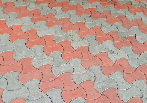Interlocking concrete paver blocks laid in an alternating red and grey wavy pattern &mdash; outdoor driveway and hardscaping concept