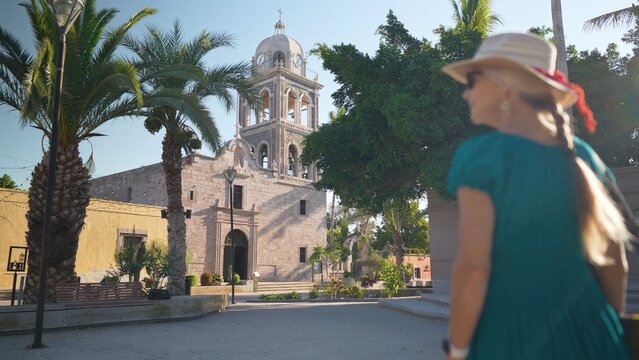 A senior woman smiles as she explores Loreto Mission church in Loreto, Baja California Sur. The sunrise adds beauty to her adventure