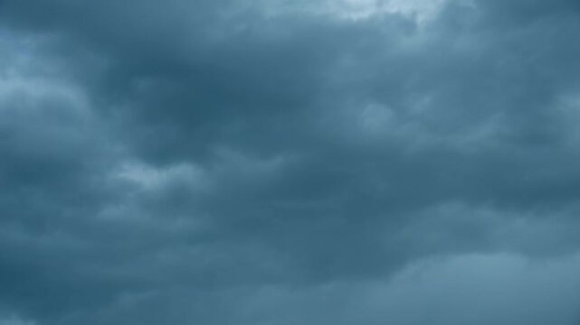 Dramatic dark storm clouds billowing across the sky before a thunderstorm, creating a menacing and ominous atmosphere in a moody meteorological weather background scene with intense cloudscape
