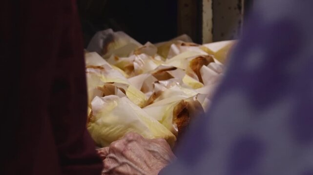Close up view of aged hands gently arranging paper wrapped cake (Jyutping) in a display rack before being covered by crowd of buying costumers showing the candid daily life and local food in Hong Kong