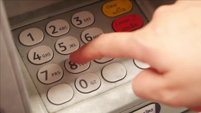 Close up of a hand pressing buttons on an ATM keypad during a bank transaction for cash withdrawal