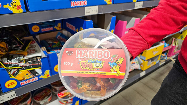 Person holding haribo gummy sweets container in supermarket