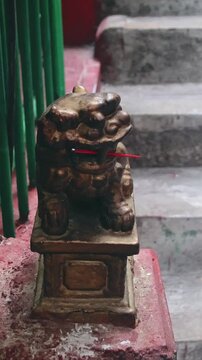 Ambient motion of the minute movements of smoke wafting across a bronze statue of a foo dog or shi shi with red incense sticks placed in its mouth. Hong Kong
