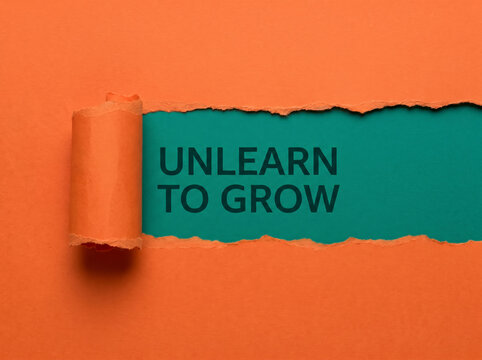 The 'Unlearn to Grow' message on torn paper reveals adaptability, transformation mindset, continuous learning and business innovation concept