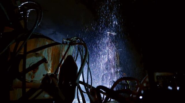 Heavy equipment operates inside a dark tunnel with water spray and intense lighting, showing underground excavation, tunnel engineering, construction machinery and infrastructure work in progress.