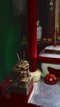 Minute movements of smoke coming from lit incense staked on a foo dog statue in an altar shrine depicting the rituals and offerings in Chinese Buddhism. Central, Hong Kong