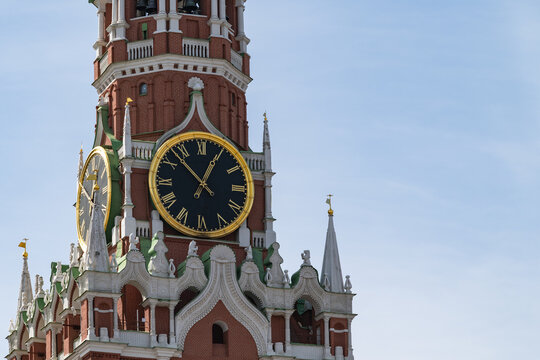 The famous clock on the Spasskaya Tower of the Moscow Kremlin against a blue sky.
