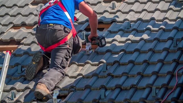 Roofer installing solar panel mounting brackets on a tiled roof