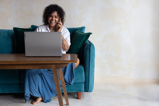 smiling woman talking on the phone, looking at laptop computer
