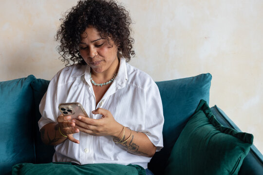 portrait of smiling woman looking at smartphone on the couch