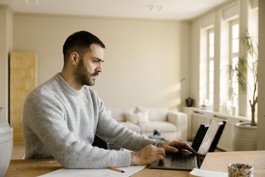Man Working on Laptop in a Modern Home Office During Daytime