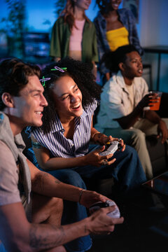 Friends laughing and playing video games together in a lounge.