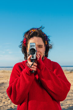 Person filming with vintage camcorder on sunny beach