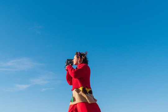 Person using vintage camcorder under clear blue sky