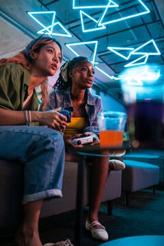 Two friends game under neon lights.