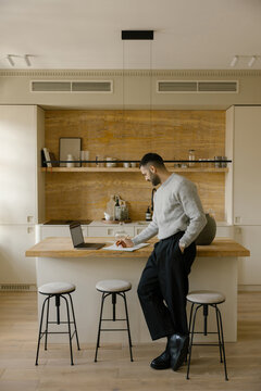 Man Working on Laptop at Kitchen Island in a Modern Home