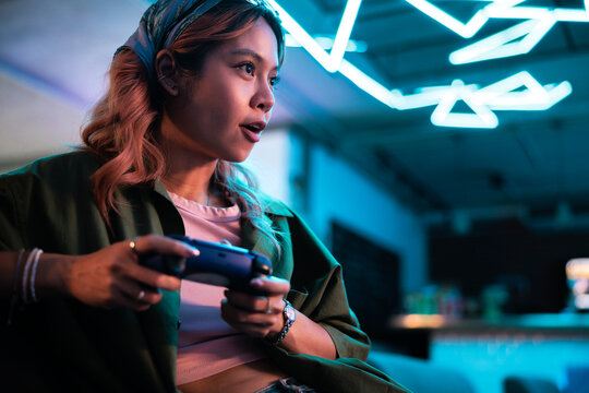 Woman intensely gaming under neon lights.