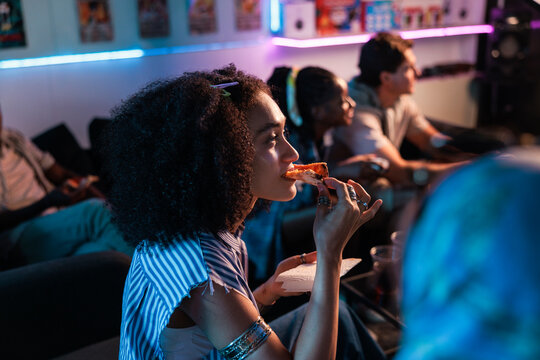 Friends gather, eat pizza, and enjoy a neon-lit hangout.