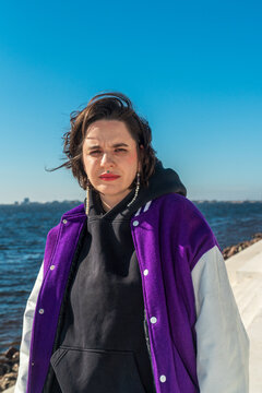 Woman portrait by sea wearing purple varsity jacket