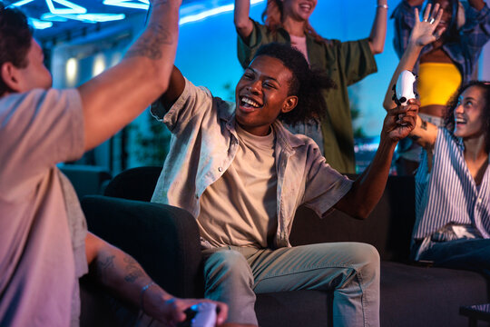 Friends celebrate a video game victory with high fives.