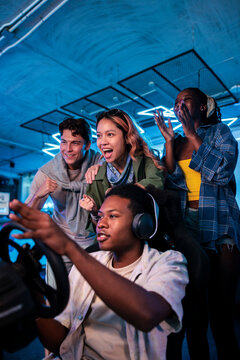 Friends cheer as one plays a racing game.