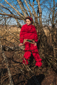 Woman in red outfit sitting on fallen tree in woodland