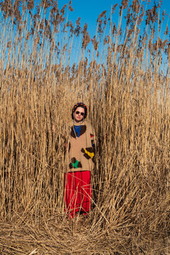 Woman standing in tall dry reeds wearing colorful outfit