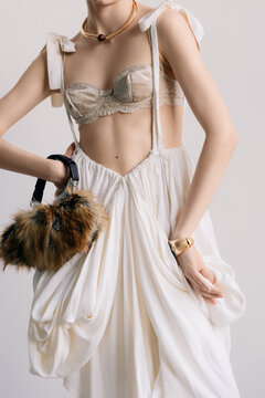Couture fashion detail with sculptural draping and fur handbag