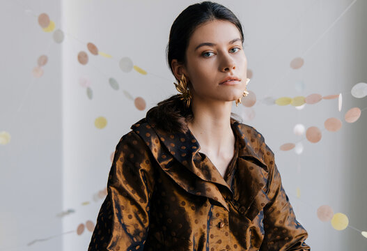 Satin editorial portrait with floral earrings and pastel decor