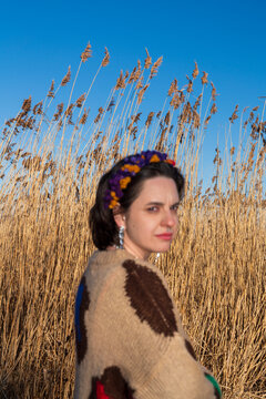 Woman with floral headband standing near tall reeds