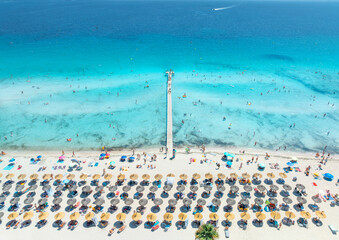Obraz na płótnie Canvas Aerial drone view of Playa de Muro sandy beach in Alcudia, Mallorca, Spain. Wooden pier in turquoise sea water, shore with straw umbrellas, sunbeds, swimming tourists. Summer holiday resort. Top view