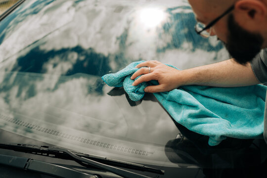 Man Cleaning Car Windshield with Microfiber Cloth