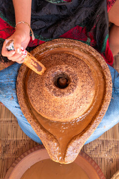 Woman grinding argan paste with traditional stone mill in Morocco