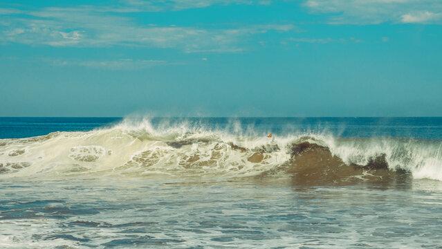 Waves crash on a beach during a sunny day in the afternoon