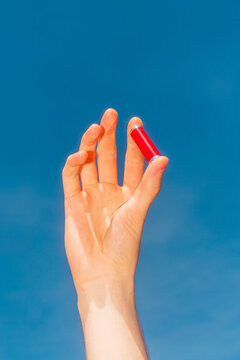 Hand holding alkaline battery against blue sky