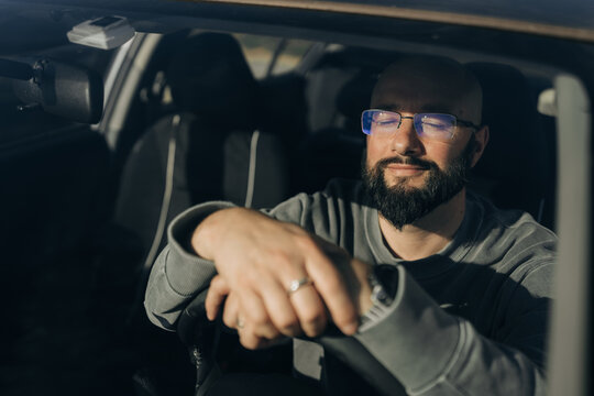 Relaxed Bearded Man Sitting Inside Car with Eyes Closed