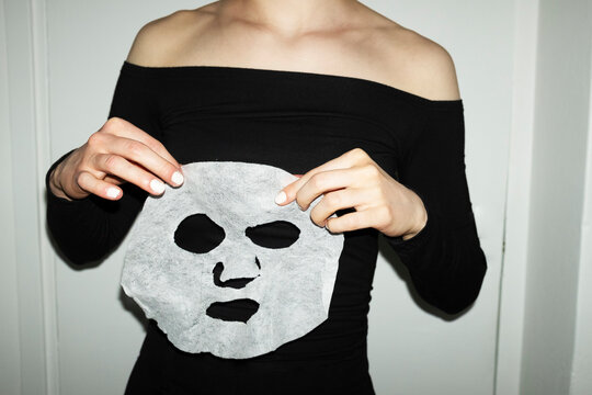 Person peeling of a beauty cosmetic facemask with hard flashlight