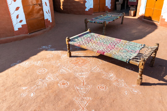 Traditional woven charpoy beds in sunlit rural courtyard