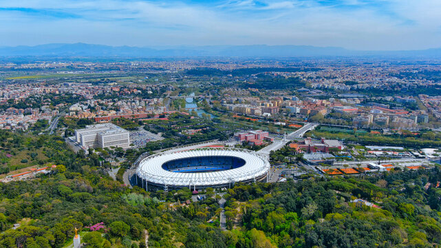 Aerial drone view of Stadio Olimpico and Foro Italico sports complex in Rome Italy featuring the Tiber River and city skyline on a sunny day.