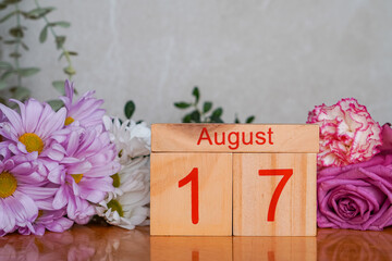 August 17, wooden calendar with colorful fresh flowers