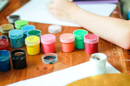 High-quality commercial stock photo showcasing early childhood education and creativity. Bright, vibrant gouache paints mixed on a plastic palette with artistic mess on a table. Perfect for school.